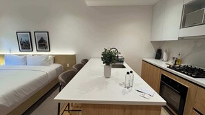 A modern hotel room with a bed, a dining table, a kitchen area, and a small plant on the table. - w* | Enchanting Loft in Roma Sur (Ciudad de México)