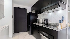 Uma cozinha moderna com armários pretos, coifa de aço inoxidável, forno embutido e bancada de granito.