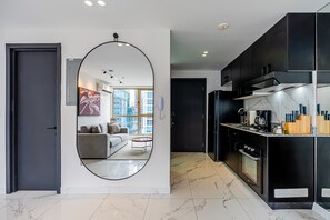 A modern kitchen with black cabinets, a marble countertop, and a large mirror. - w* | Polished 1BR in Obarrio w/ Pool (Panamá)