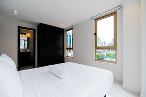 Una habitación de hotel con cama, baño y vista a la ciudad desde la ventana.