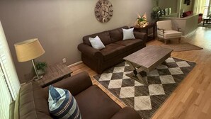 Una sala de estar con un sofá marrón, una mesa de centro de madera y una alfombra estampada.