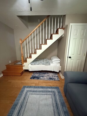 A staircase leading to a loft bedroom with a bed and a door to the right.