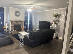 Un salon avec une cheminée, un téléviseur, un canapé et une table basse.