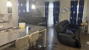 A modern kitchen with a granite countertop, a piano, and a dining area with a leather sofa. - Charming 3-bedroom house pleasant Dallas (dallas)