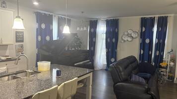 A modern kitchen with a granite countertop, a piano, and a dining area with a leather sofa.
