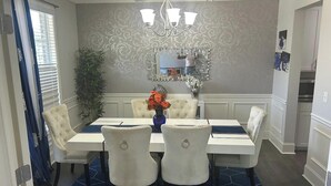 A dining area with a chandelier, patterned wallpaper, and a blue rug. - Charming 3-bedroom house pleasant Dallas (dallas)