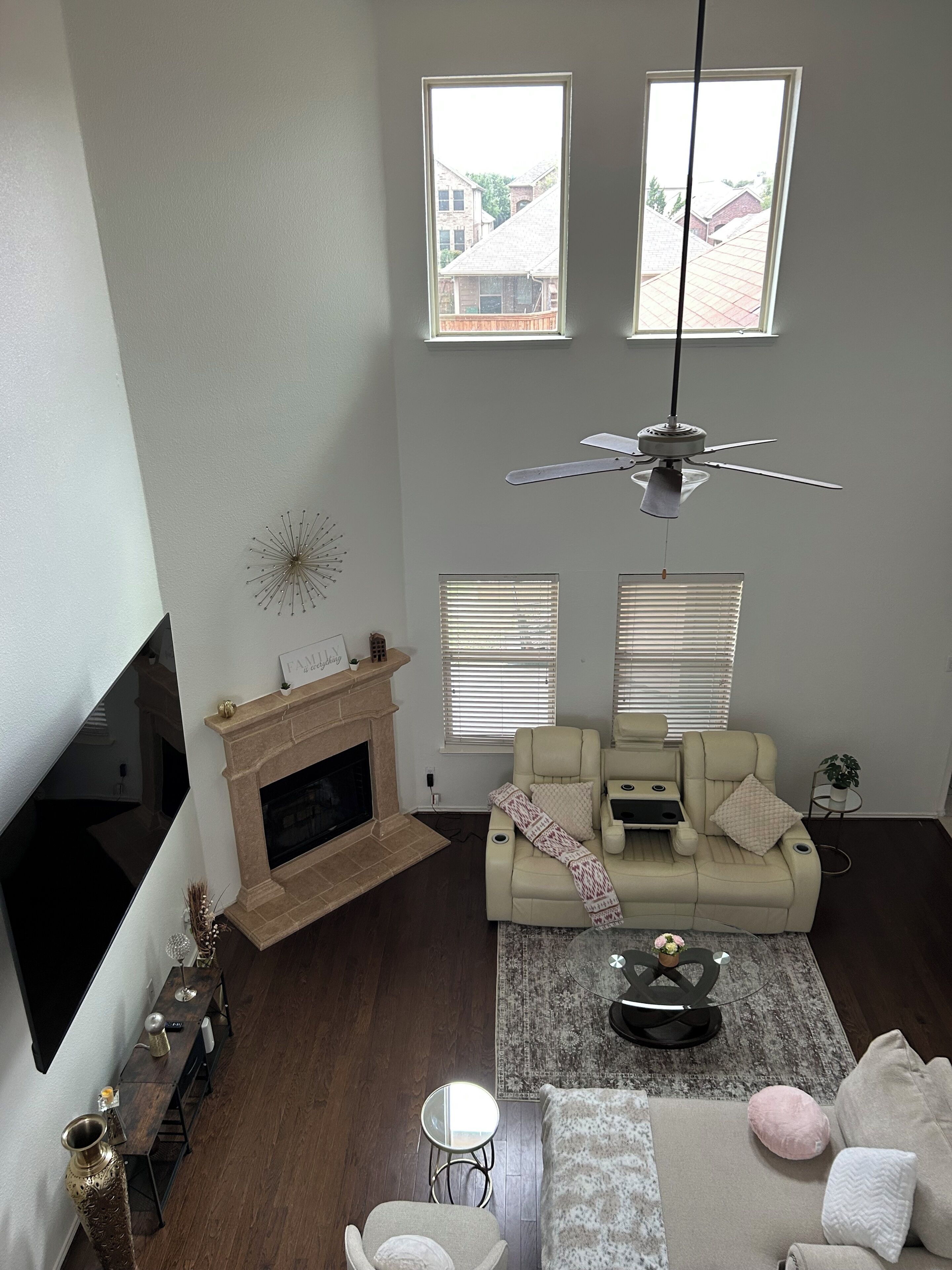 A living room with a fireplace, a sofa, a coffee table, and a ceiling fan.