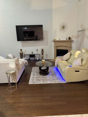 Una sala de estar moderna con un sofá, una mesa de centro, un televisor de pantalla plana montado en la pared y una chimenea.