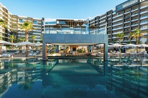Ein modernes Hotel mit einem zentral gelegenen Pool, mehreren Balkonen und Außenbereichen zum Sitzen.