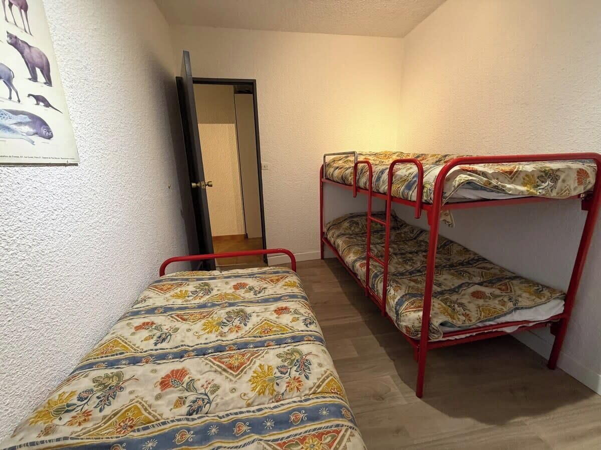 Una habitación pequeña con dos literas, una puerta y un póster en la pared.