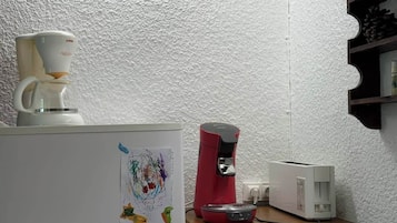 A kitchenette with a coffee maker, a toaster, and a refrigerator.