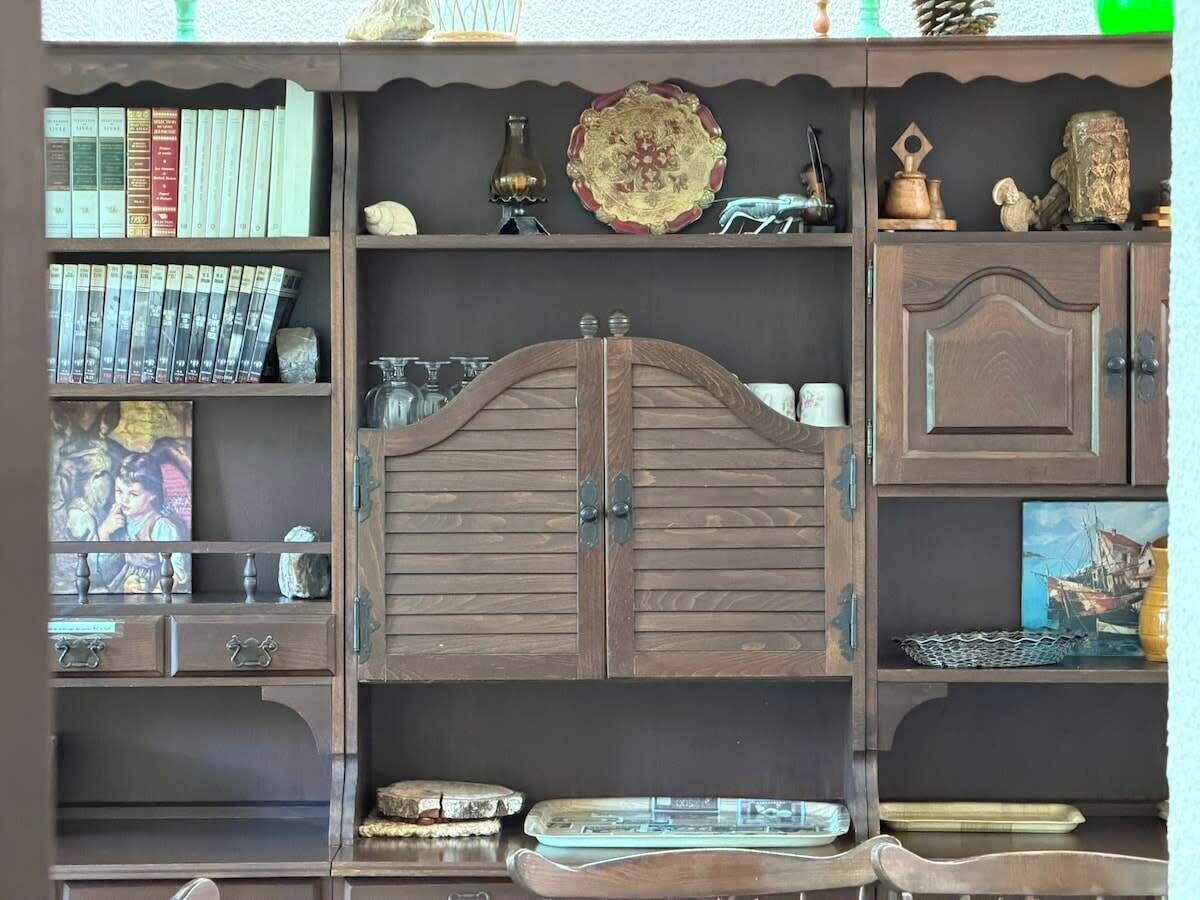 Ein Bücherregal mit Büchern, Dekorationen und einem zentralen Holzschrank.