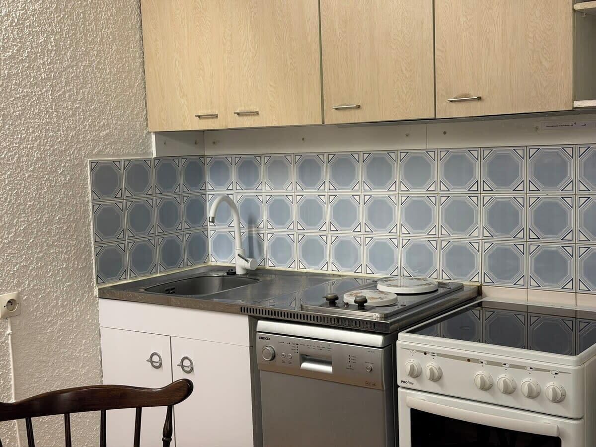 Une cuisine de taille réduite équipée d’un lave-vaisselle, d’une cuisinière et d’un évier avec un robinet.