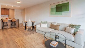 Uma sala de estar moderna com um sofá, mesa de centro e área de jantar com cadeiras e uma mesa.