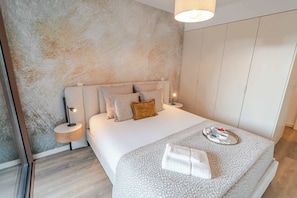 Ein modernes Schlafzimmer mit Bett, Nachttischen, einem Schrank und einer strukturierten Wand.
