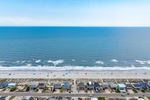 Eine Küstenstraße mit Strandhäusern und einem Strand mit Sonnenschirmen.
