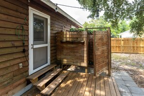 A wooden deck with a bench, a wooden structure with a window, and a fence in the background. - Pet-Friendly Oak Island Home W/ Fenced Yard &Fire Pit (Oak Island)