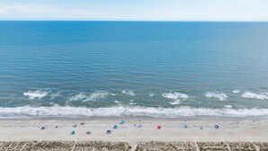 A beach with a clear view of the ocean, sandy shore, and beach umbrellas.