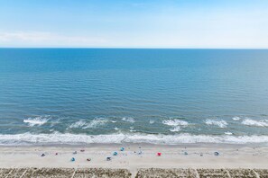 A beach with a clear view of the ocean, sandy shore, and beach umbrellas. - Pet-Friendly Oak Island Home W/ Fenced Yard &Fire Pit (Oak Island)