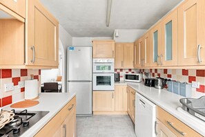 Una cocina moderna con armarios de madera, un refrigerador, horno, microondas y lavavajillas.