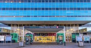The entrance to a modern building with a sign reading 'Welcome to Milton Keynes Central.'