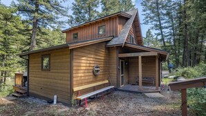 A wooden cabin with a porch, a bench, and a small outdoor seating area.