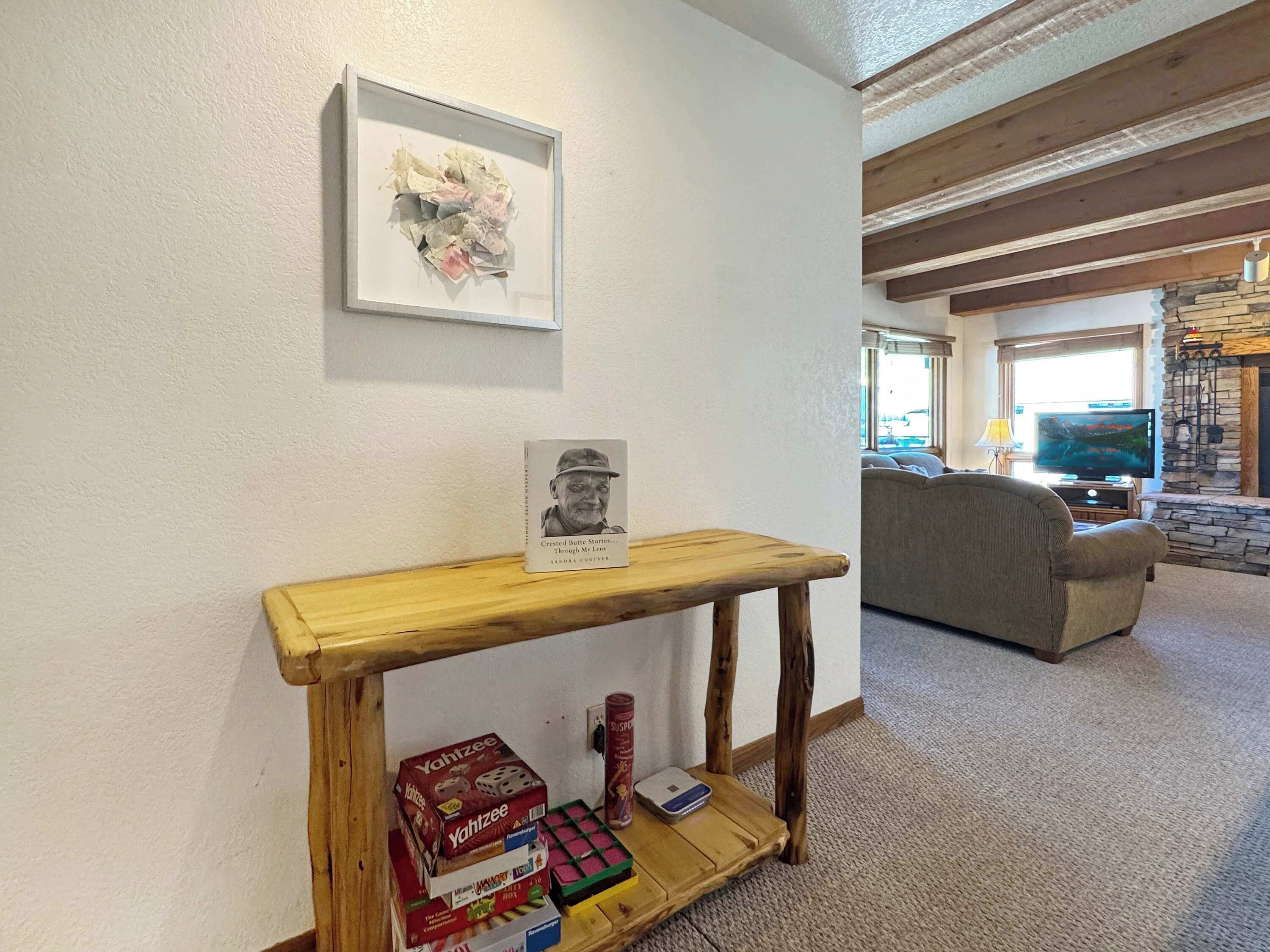 A living room with a wooden console table, a framed picture, a bookshelf, a couch, and a stone fireplace.