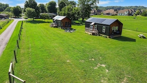 Een landelijk gelegen bezit met twee huisjes, een omheind pad en een grasveld.