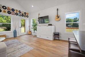 Una habitación amplia con un ventanal grande, un televisor de pantalla plana, una guitarra y una colección de discos de vinilo en la pared.