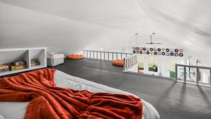 A spacious attic bedroom with a high ceiling, a large bed, a cozy orange bean bag, and a collection of vinyl records on the wall. - Hidden Gem Farm-Two Tiny Homes-Sleeps 11 (Spring Hill)