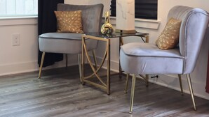 A room with two grey armchairs, a small table with a lamp, and a window with black curtains. - New Gated Home Near the Texas Medical Center: Workspace + Yard +Fast Wifi (Houston)