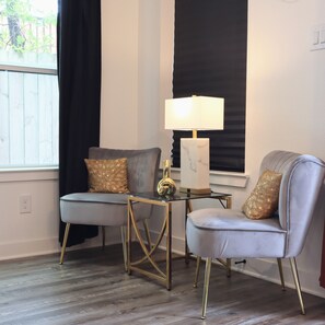 A room with two grey armchairs, a small table with a lamp, and a window with black curtains. - New Gated Home Near the Texas Medical Center: Workspace + Yard +Fast Wifi (Houston)