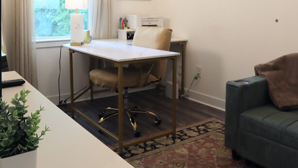A room with a desk, chair, and a couch. There's a window with curtains, a lamp, and a wall-mounted mirror. - New Gated Home Near the Texas Medical Center: Workspace + Yard +Fast Wifi (Houston)