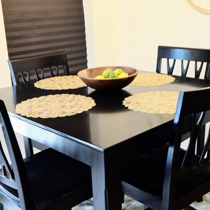 A dining table with a bowl of fruit in the center, surrounded by four chairs. - New Gated Home Near the Texas Medical Center: Workspace + Yard +Fast Wifi (Houston)