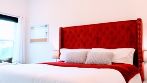A hotel room with a large bed, white bedding, and a red headboard. - New Gated Home Near the Texas Medical Center: Workspace + Yard +Fast Wifi (Houston)