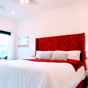 A hotel room with a large bed, white bedding, and a red headboard. - New Gated Home Near the Texas Medical Center: Workspace + Yard +Fast Wifi (Houston)