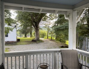 A covered porch with a view of a grassy area and trees. - Build memories in WNC! (Brevard)