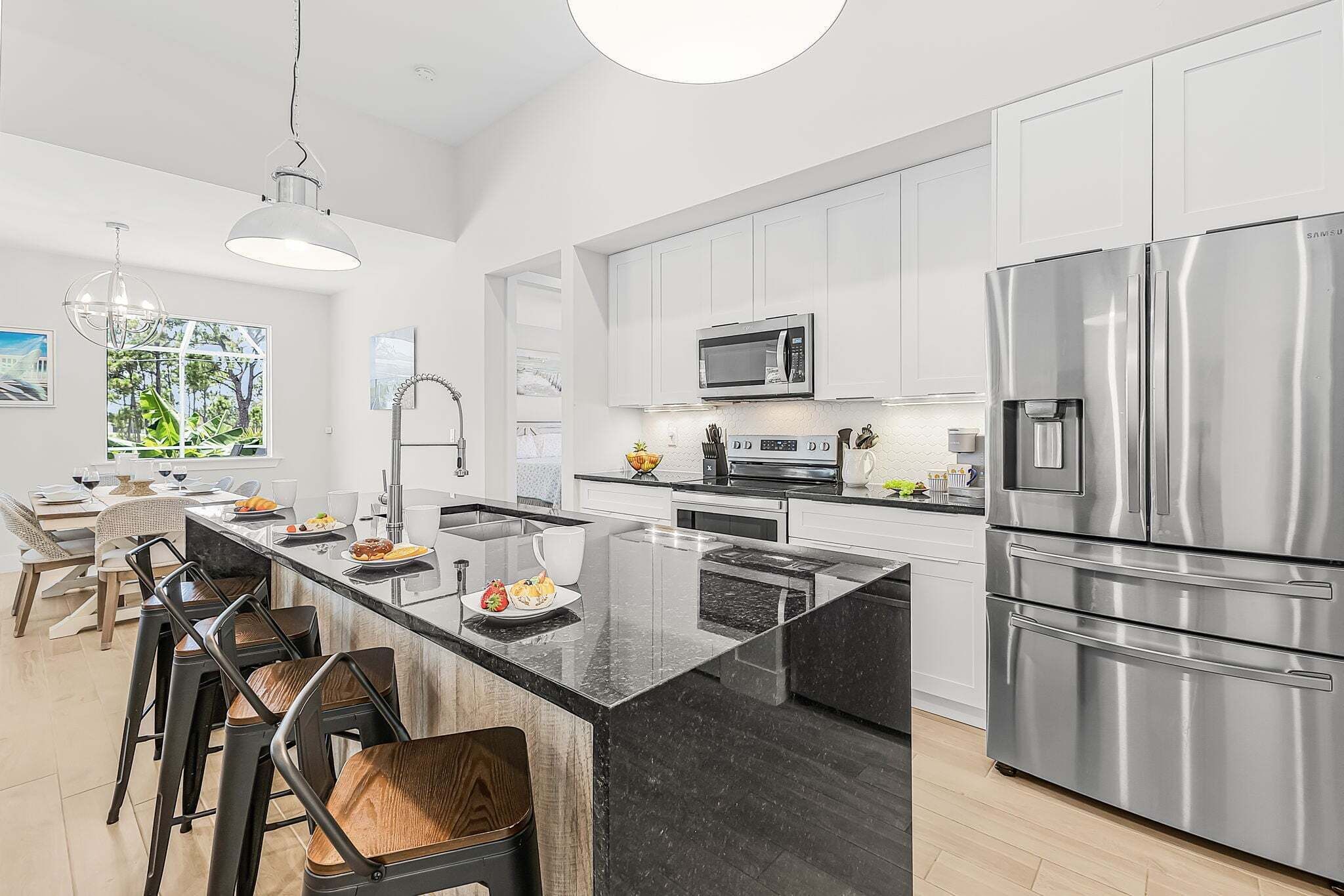 A modern kitchen with a central island, stainless steel appliances, and a dining area with bar stools.