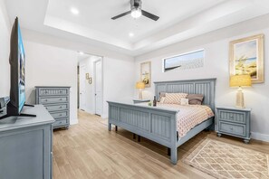 Ein Schlafzimmer mit einem Bett, Nachttischen, einem Schreibtisch und einem Deckenventilator.