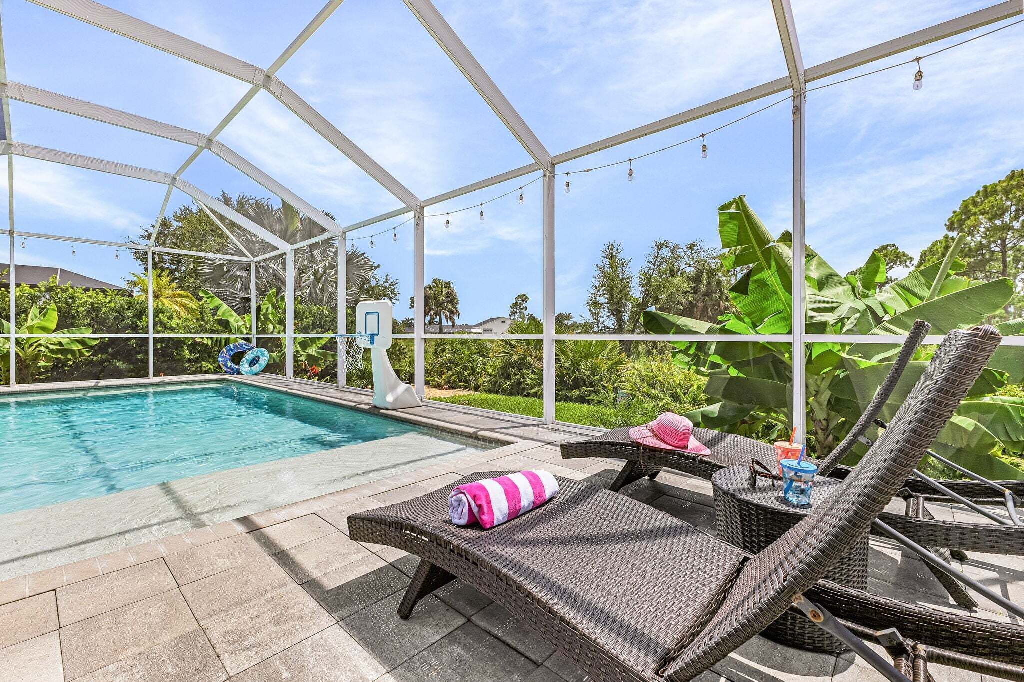 Un espace piscine doté d’une structure en verre, de chaises longues et d’une petite table avec des boissons.