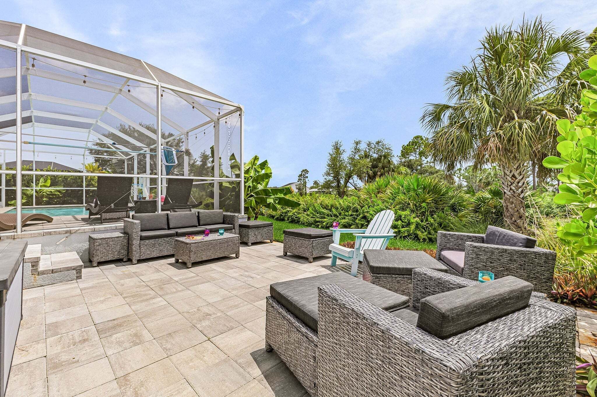 A covered outdoor seating area with wicker furniture and a glass enclosure.