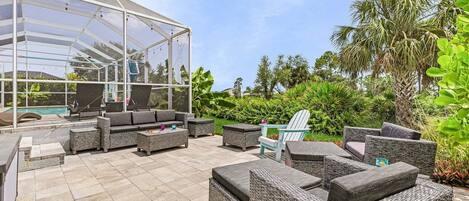 A covered outdoor seating area with wicker furniture and a glass enclosure.