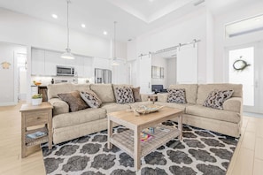 Ein modernes Wohnzimmer mit einer Eckcouch, einem Couchtisch und einem gemusterten Teppich.