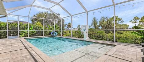 A covered swimming pool with a clear blue water surface, surrounded by a white metal frame structure.