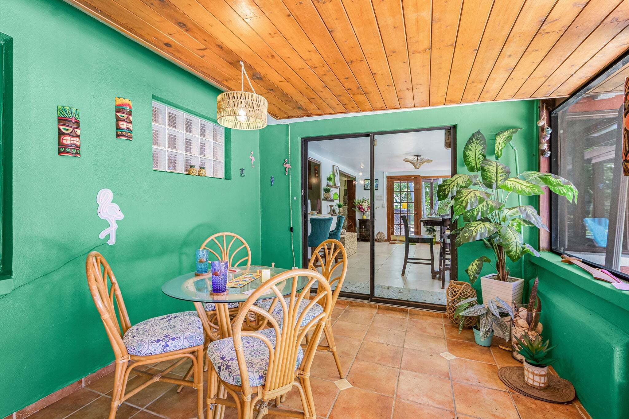 A dining area with a round table and chairs, a wooden ceiling, and a green wall with decorative elements.