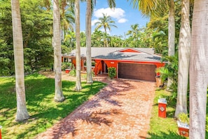 A residential property with a brick driveway, a garage, and a red house with a number 4250 garage door. - Tropical Retreat with Heated Pool, Spa & Tiki Bar - Coastal Paradise Getaway - Roelens (Cape Coral)