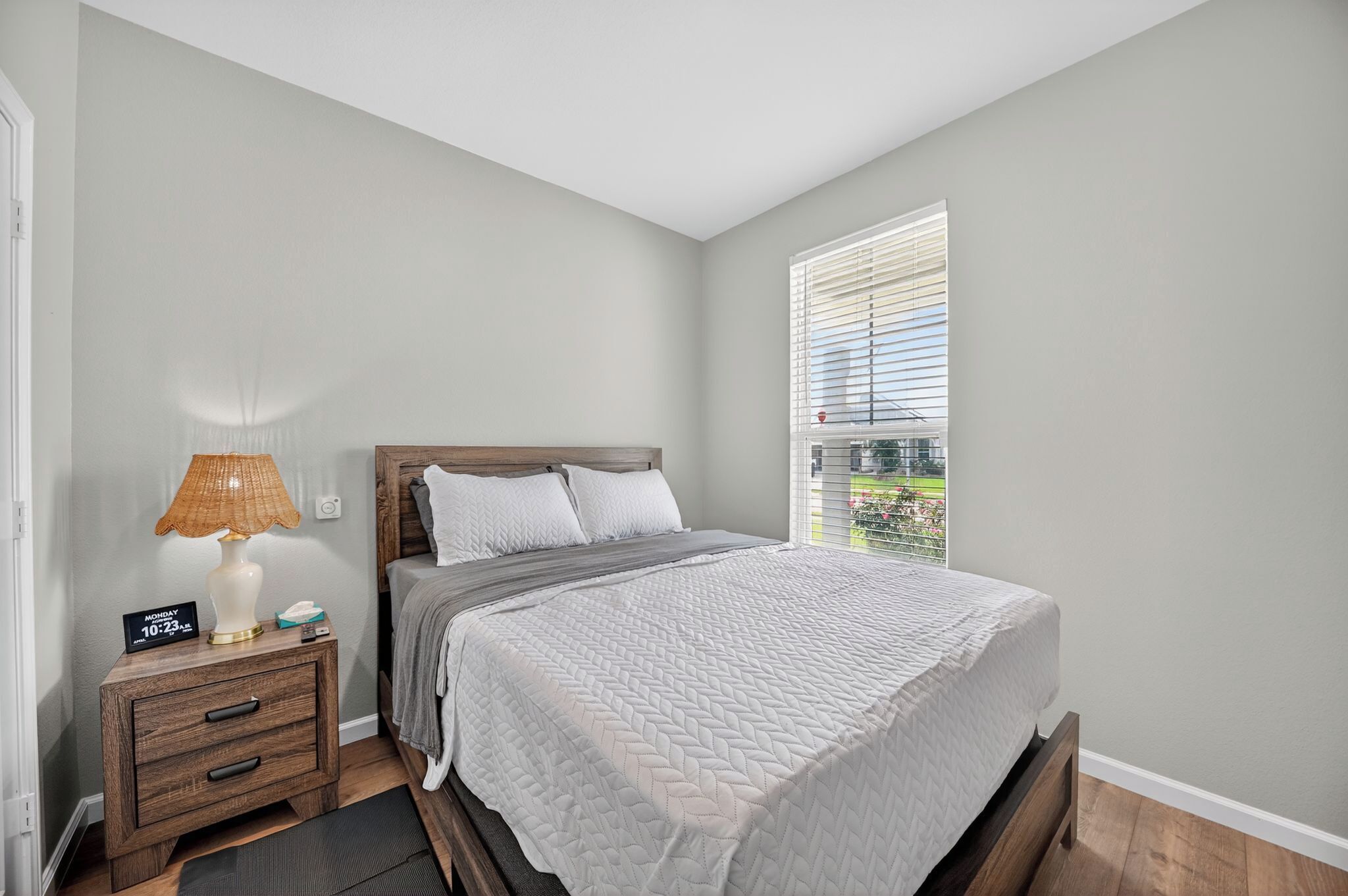 Une chambre à coucher avec un lit, une table de chevet, une lampe et une fenêtre avec des stores.