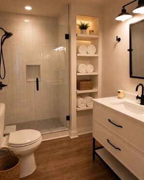 A modern bathroom with a glass-enclosed shower, white tiled walls, a white sink with black handles, and neatly rolled towels on shelves. - Old City Marsh View Retreat Pets Welcome (St. Augustine)