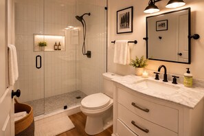 A modern bathroom with a glass-enclosed shower, a toilet, a vanity with a mirror, and a sink. - Old City Marsh View Retreat Pets Welcome (St. Augustine)