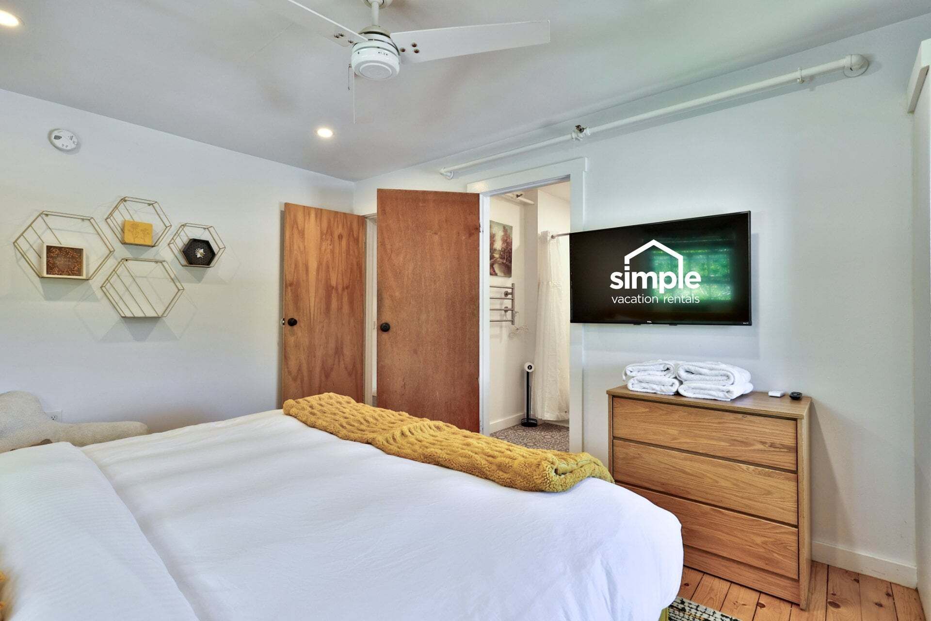 Habitación de hotel con cama, televisor, cómoda de madera y armario.